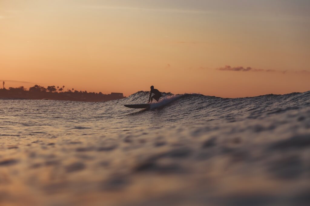 Man on surf board on water wave at sunset